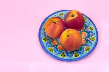 Pastel pembe arka plan ve kopyalama alanı ile Talavera plaka merkezli Şeftali