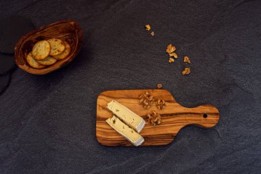 Beton arka plan ve kopyalama alanı ile ahşap plaka peynir, kraker ve fındık üst görünümü