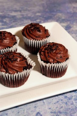 Kopya alanı ile kare beyaz plaka ve mavi bulanık arka plan üzerinde Çikolata cupcakes
