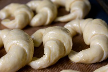 Ready to bake, raw Argentine croissants, medialunas de Manteca over silicon pastry mat close up  clipart