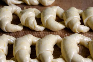 Pişirmeye hazır, çiğ Arjantin kruvasanı, silikon hamur işi arka planında medialunas de Manteca 