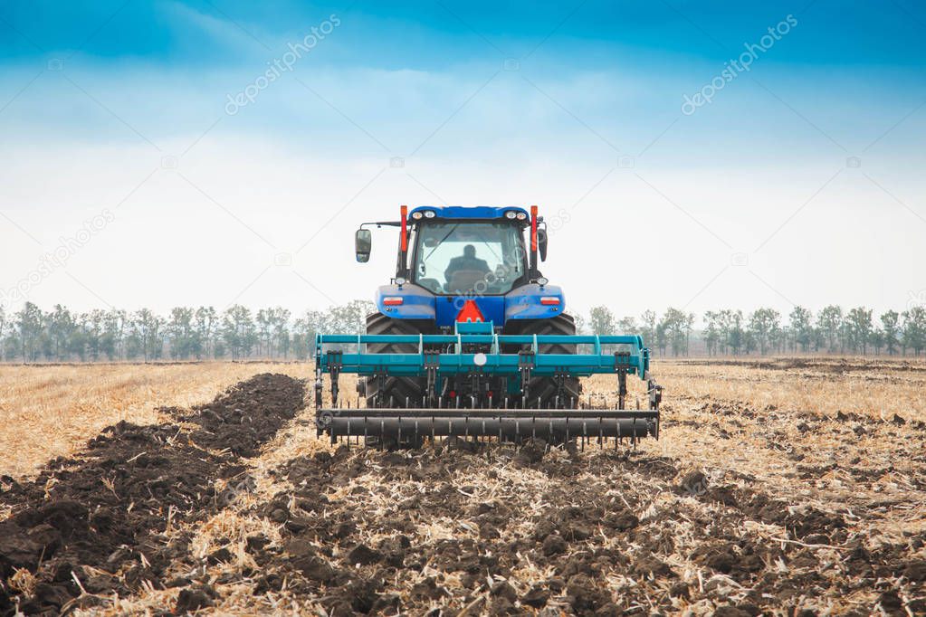 Modern tractor in a field on a sunny day. The concept of work in a fields and agriculture industry.