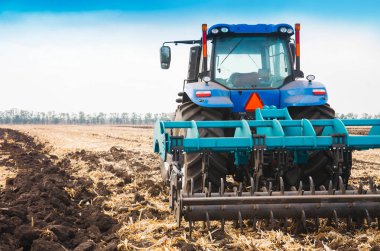 Açık bir günde sürülmüş bir alana modern bir traktör. Tarım Sanayi kavramı.