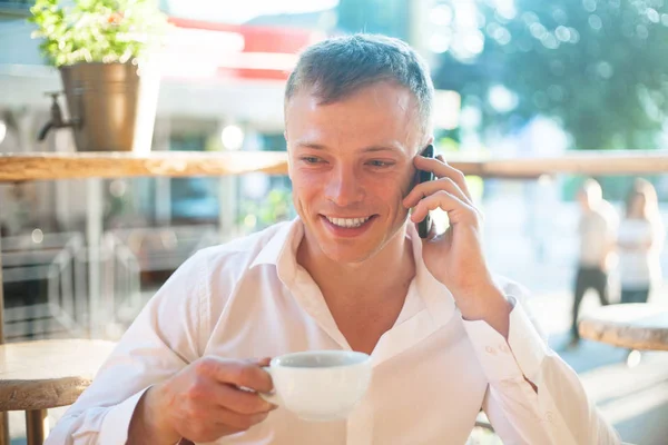 カフェでコーヒーを飲みながら携帯電話を使用して若い男 ビジネス人々 屋外ポートレート — ストック写真