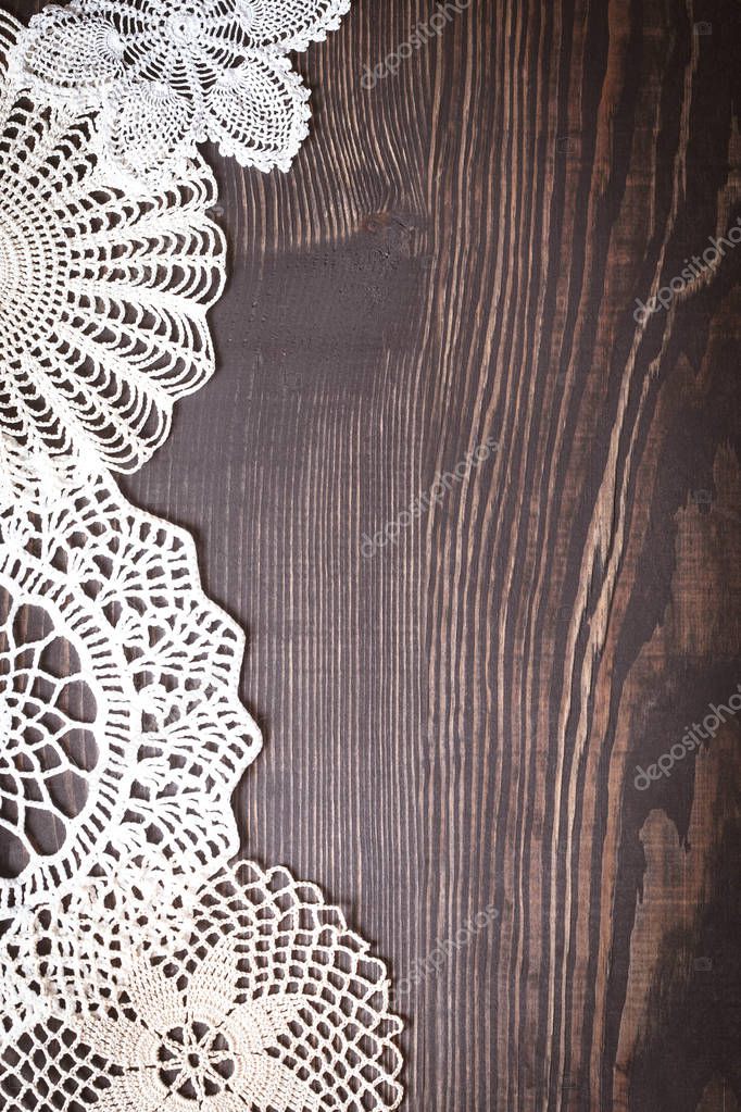 Vintage knitted lace on the background of wooden boards. Background in retro style.