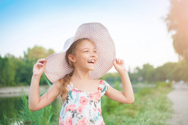 都市の外の自然の中の夏の夜に沈む夕日の光線でピンクの帽子で美しい少女 — ストック写真