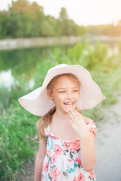 一个美丽的女孩穿着粉红色的帽子在日落的阳光下 在城市外的自然夏日夜晚 — 图库照片