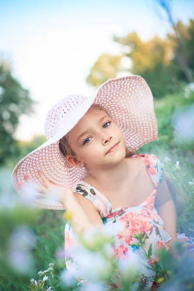 美丽的女孩在一个粉红色的帽子夏天在一个绿色的花园中的花朵 — 图库照片
