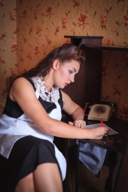 Masada oturan ve bir belgeyi imzalamadan güzel kadın. Retro tarzı, vintage.