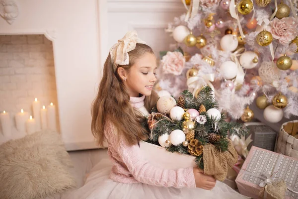 Bella bambina con un vestito seduto vicino all'albero di Natale. Vacanze invernali. Felice anno nuovo — Foto Stock