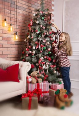 Sevimli kız Noel ağacı süsle. Kış tatil kavramı.