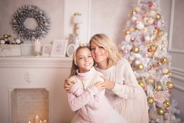 Bella giovane madre con sua figlia negli interni di Capodanno vicino all'albero di Natale . — Foto Stock