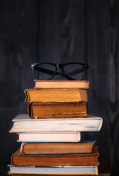 暗い背景の木に老眼鏡のハードカバー書籍のスタック 学校に戻る — ストック写真