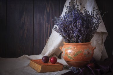 Lavanta, bir kitap ve Erik masada bir buket ile natürmort. Ülke stil.