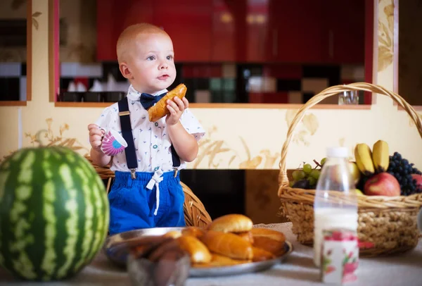 Little boy eating a pie in the kitchen at the table. Shooting in the interior in retro style.