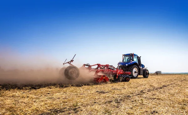 The tractor plows the field, cultivates the soil for sowing grain. The concept of agriculture and agricultural machinery.