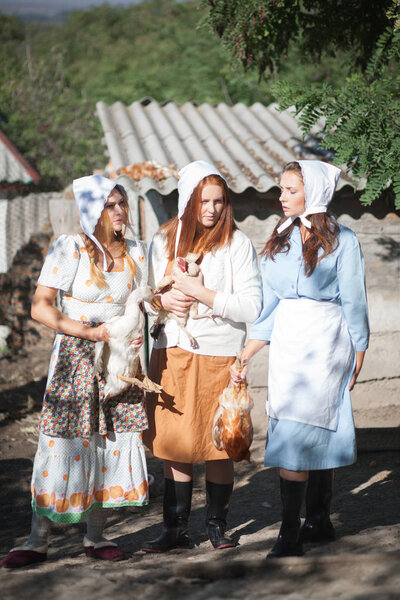Three women with poultry in their hands. Shooting in retro style.