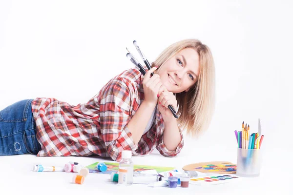 Portret van een jonge vrouw met borstels in haar handen in de studio. — Stockfoto