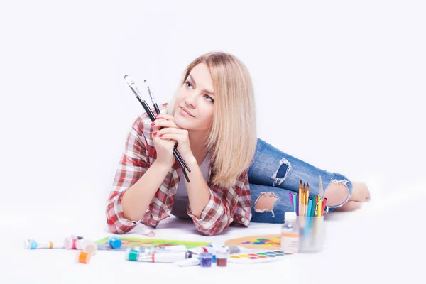 Portret van een jonge vrouw met borstels in haar handen in de studio. — Stockfoto