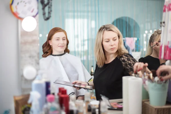 Maître maquille une jeune femme dans le salon . — Photo