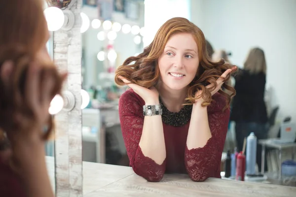 Kobieta w salonie kosmetycznym patrzy na jej odbicie w lustrze i sprawdza fryzurę. — Zdjęcie stockowe