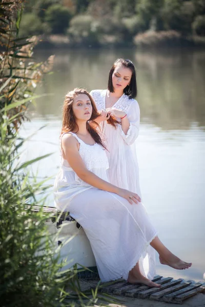 İki genç kadın Nehri yakınında uzun beyaz elbiseler. — Stok fotoğraf
