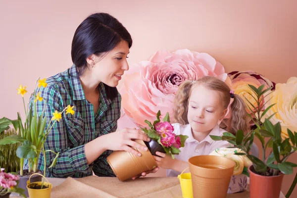 Schattig kind meisje helpt haar moeder om de zorg voor planten. — Stockfoto