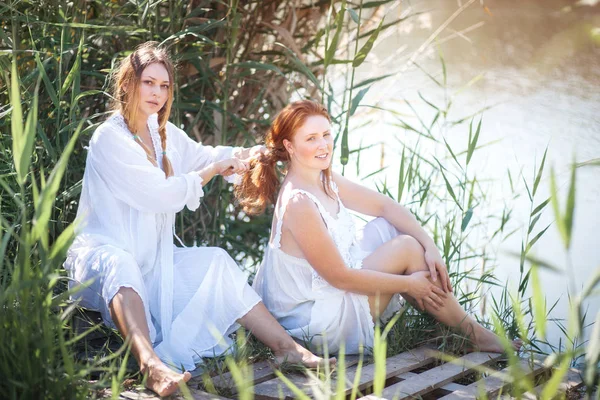 河边穿着白色长裙的两名年轻女子. — 图库照片