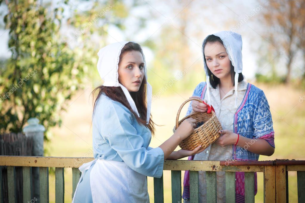 Two young women talking standing near the fence.