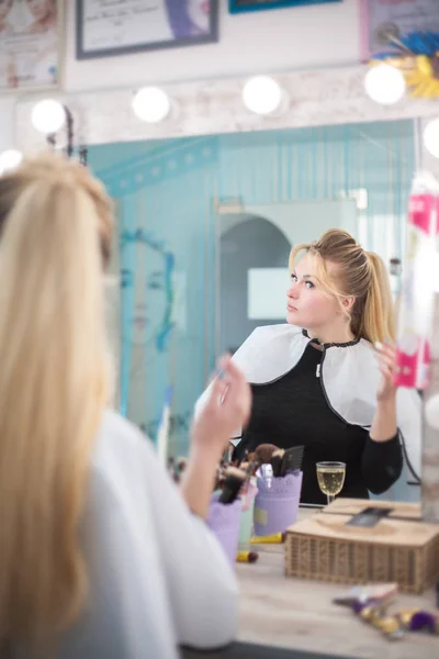 Femme dans un salon de beauté regarde son reflet dans le miroir et vérifie la coiffure . — Photo