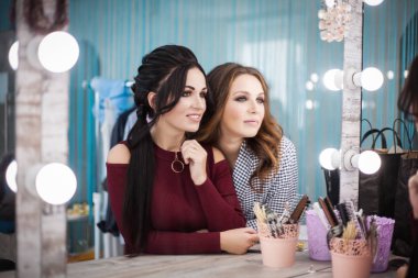 İki güzel genç kadın güzellik salonunda aynaya bakmak. Saç ve makyaj.