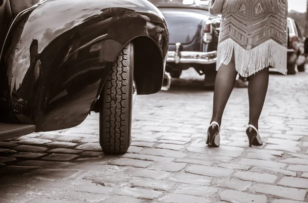 Beine einer Frau, die aus einem alten Auto steigt. junge Frau in Stöckelschuhen. — Stockfoto