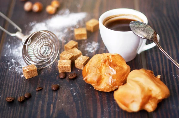 Tazza di caffè nero caldo con profiteroles fatti in casa su un tavolo rustico — Foto Stock