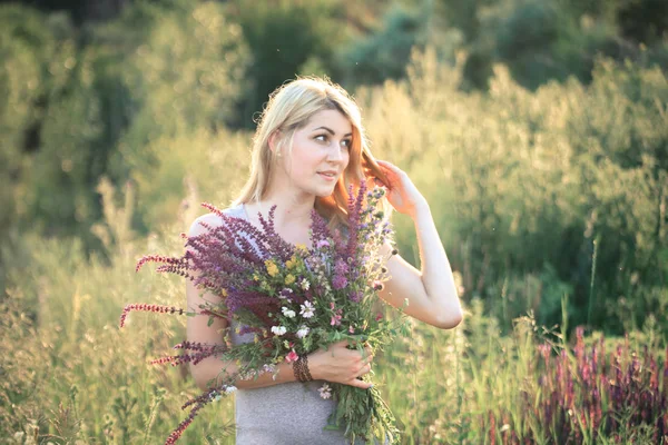 Ritratto di una giovane bella donna nella natura con un mazzo di fiori . — Foto Stock