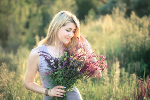 Porträt einer jungen schönen Frau in der Natur mit einem Blumenstrauß. — Stockfoto