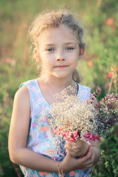 夏天在田野里，一束鲜花捧着一束鲜花的大自然的小女孩. — 图库照片