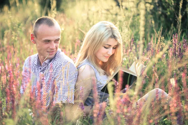 Young couple in the summer on the nature reading a book. The concept of relationships, love and relaxation. — Stock Photo, Image