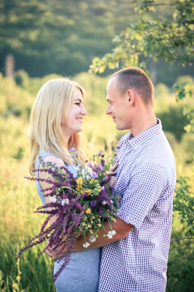 Man and woman on nature with a bouquet of flowers. Couple in love. — Stock Photo, Image