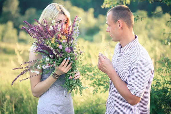 Mann und Frau in der Natur mit einem Blumenstrauß. Verliebtes Paar. — Stockfoto