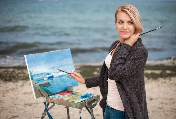 Молодая женщина-художник рисует пейзаж на пляже . — стоковое фото