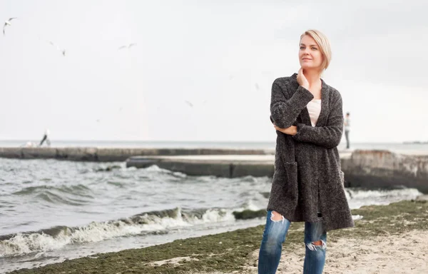 Atraktivní žena nosí teplý svetr v chladné beach. — Stock fotografie