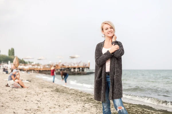 Atraktivní žena nosí teplý svetr v chladné beach. — Stock fotografie