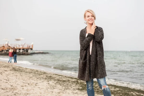 Atraktivní žena nosí teplý svetr v chladné beach. — Stock fotografie