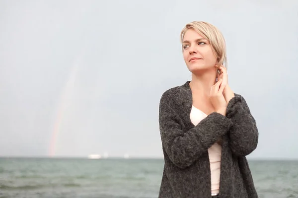 Attractive woman wearing a warm cardigan at the cold beach. — Stock Photo, Image