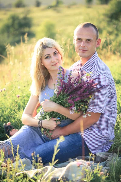 Man and woman on nature with a bouquet of flowers. Couple in love. — Stock Photo, Image