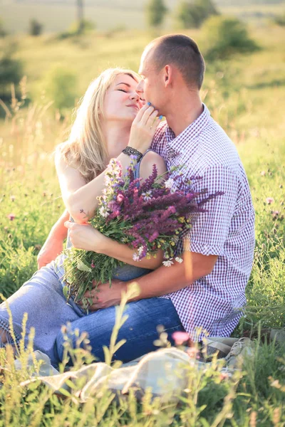 Hombre y mujer en la naturaleza con un ramo de flores. Pareja enamorada . — Foto de Stock
