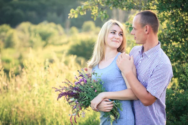 Man and woman on nature with a bouquet of flowers. Couple in love. — Stock Photo, Image
