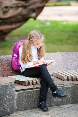 Kız öğrenci bir sırt çantası ve kitap açık havada. Eğitim ve öğrenme konsepti.
