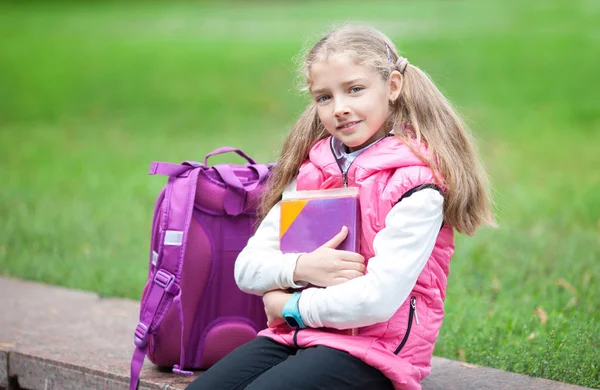 Skolflicka med ryggsäck och boka utomhus. Utbildnings-och inlärnings koncept. — Stockfoto
