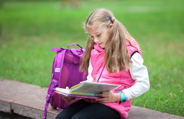 Écolière avec un sac à dos et réserver à l'extérieur. Concept d'éducation et d'apprentissage . — Photo